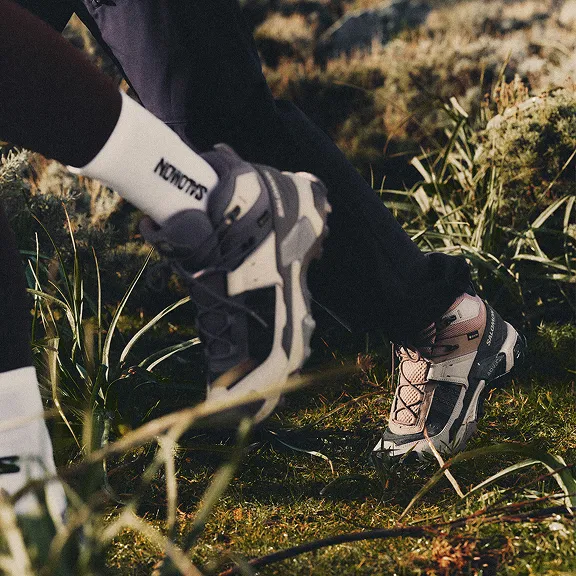 Zwei Personen beim Wandern, Fokus auf Salomon-Schuhe im Gras.