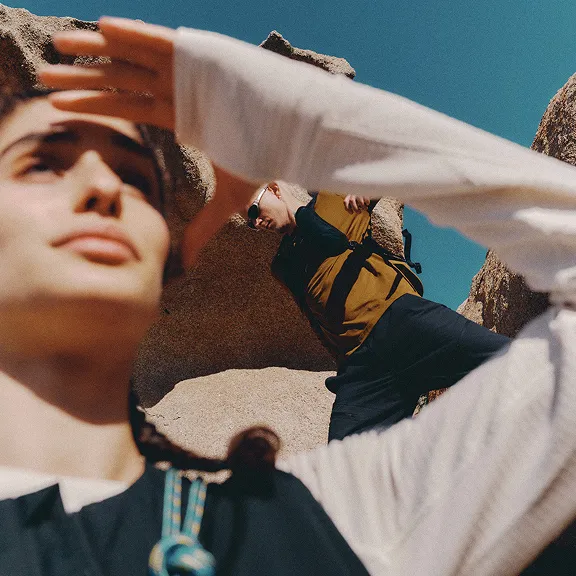 Zwei Wanderer zwischen Felsen, einer schützt die Augen vor der Sonne.