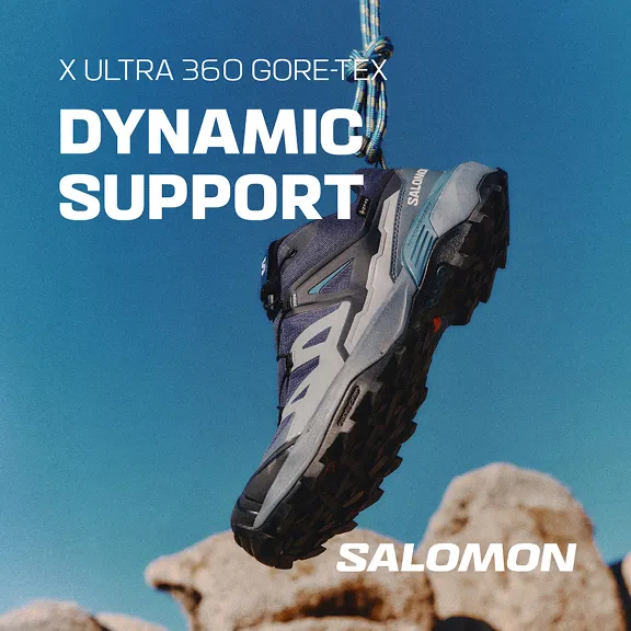 Salomon X Ultra 360 Gore-Tex Wanderschuh am Seil mit Felsen im Hintergrund.